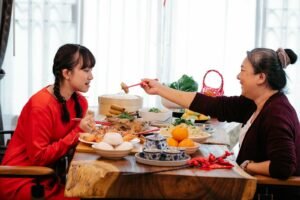 A grandmother and granddaughter share a joyful meal celebrating Lunar New Year, a symbol of togetherness and tradition.